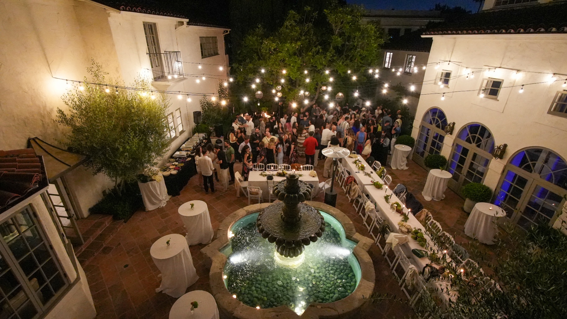 Fountain courtyard glowing with string lights during a night event