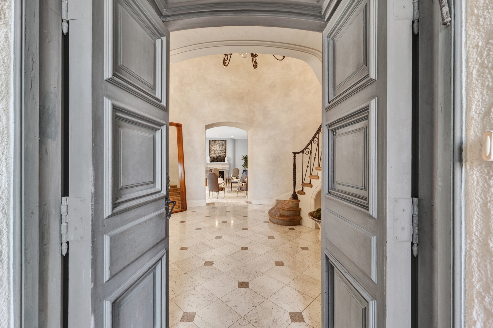 Grand entry doors opening to the marble foyer