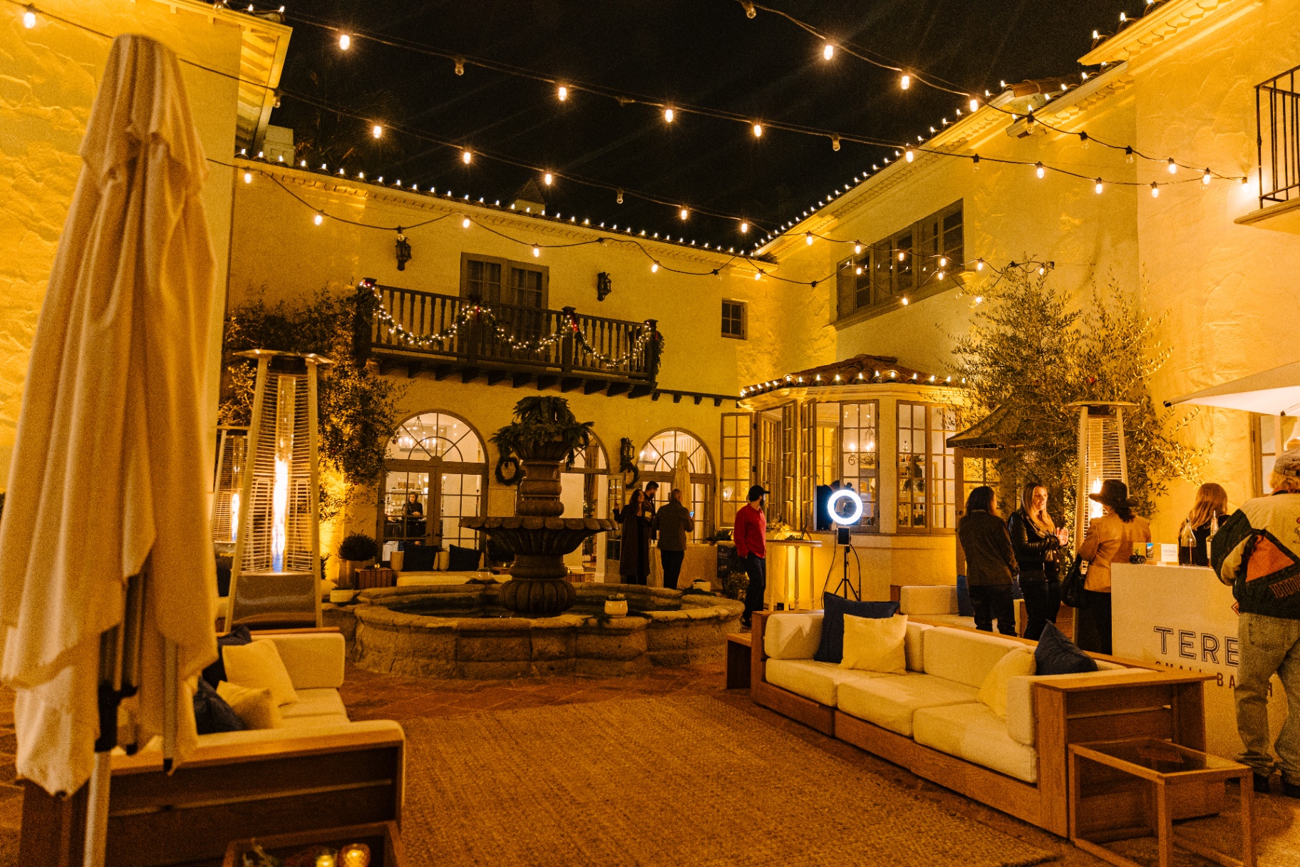Night courtyard glowing with string lights and fountain