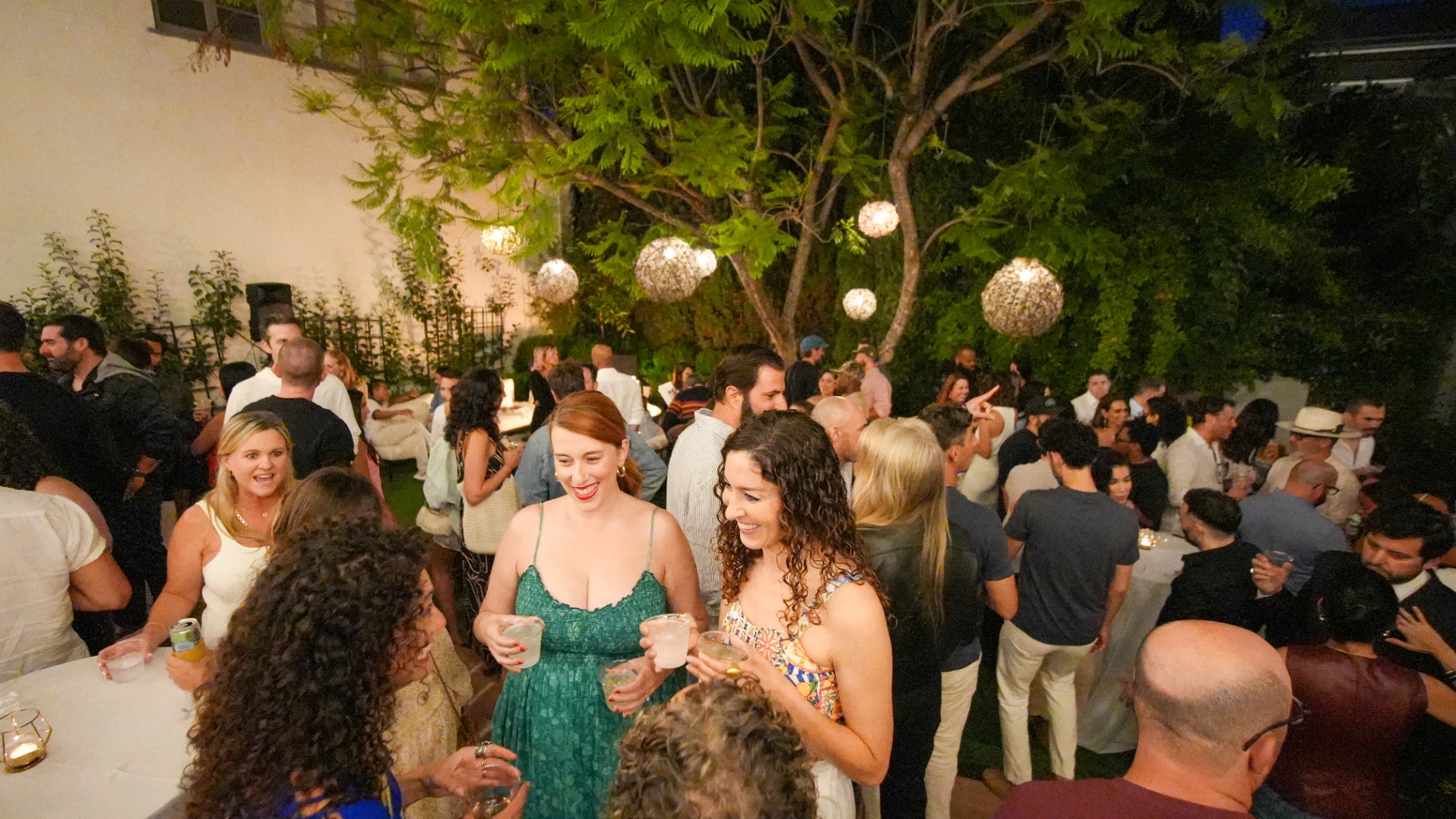 Cocktail crowd under woven pendant globes at night