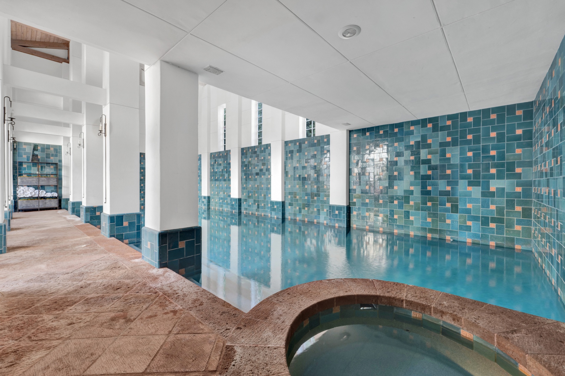 Indoor pool with adjacent circular spa and tiled walls