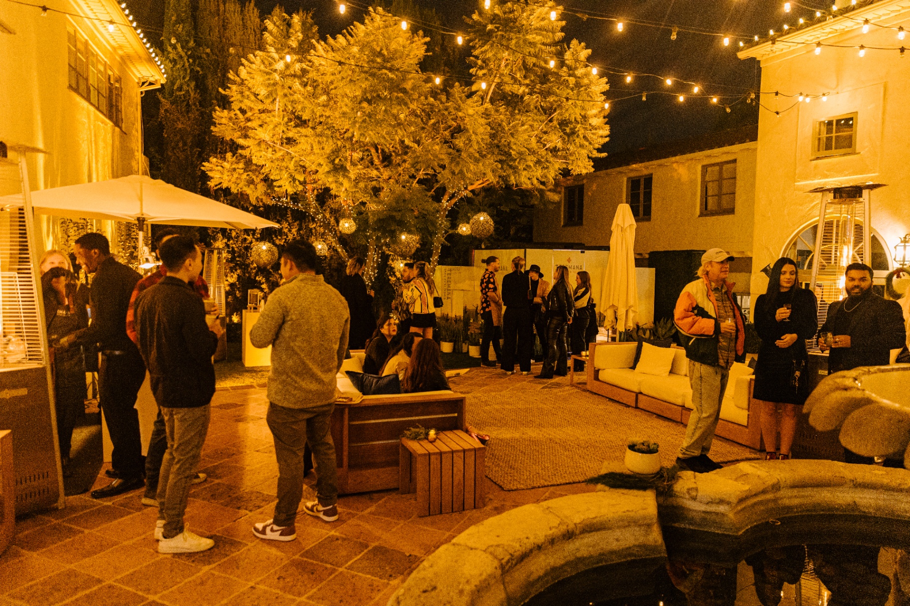 Guests gathered under a lit tree with woven pendants