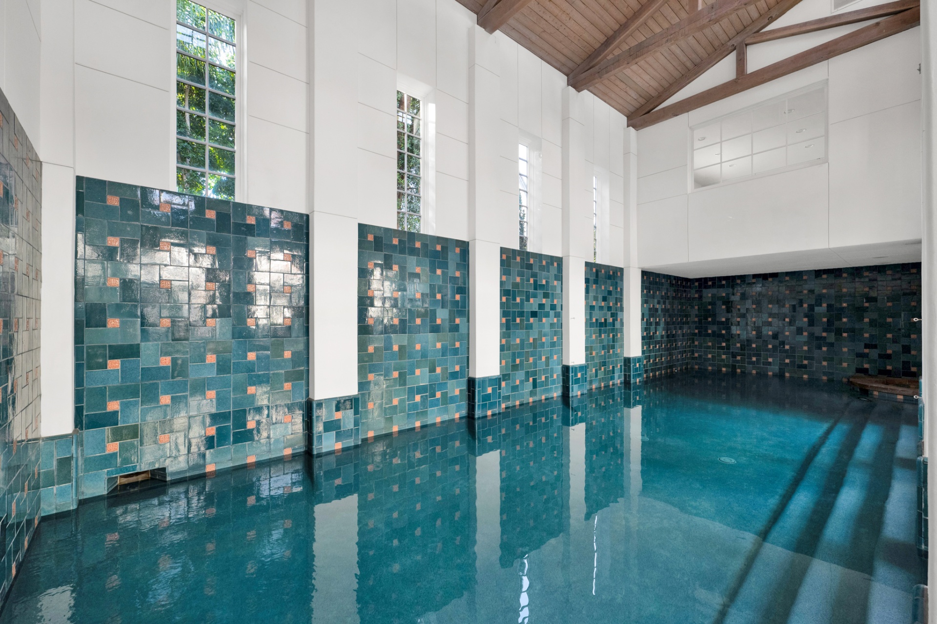 Andalusian bathhouse-inspired indoor pool with emerald tilework and timber trusses